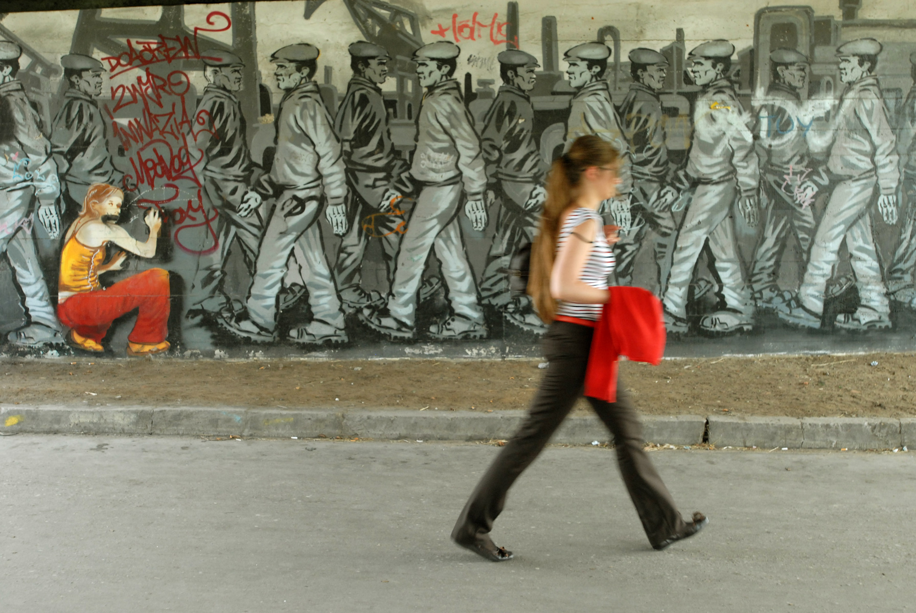 A woman passes by a mural created during Monumental Art Festival in Gdansk.