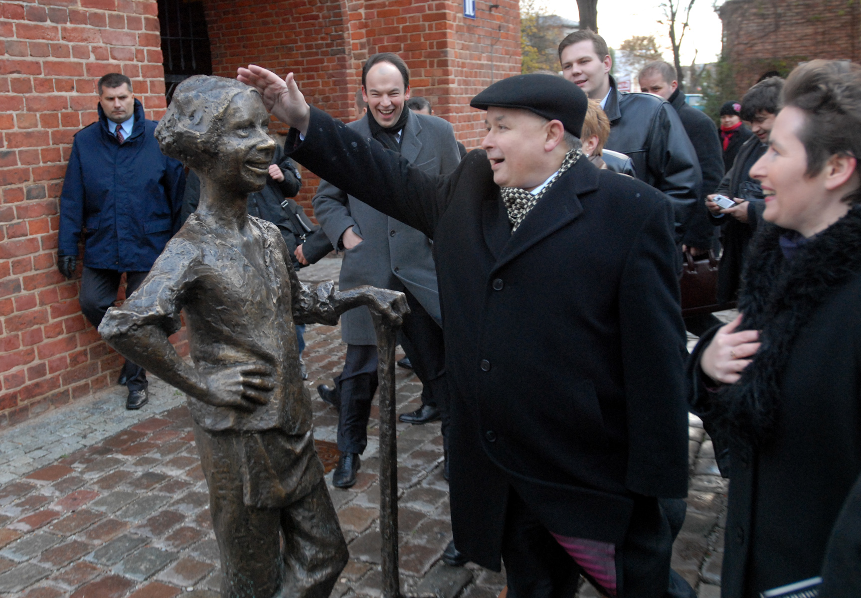 Premier Jarosław Kaczyński dotyka pomnika piekarczyka na Starym Mieście w Elblągu. Dotknięcie posągu wg mieszkańców Elbląga przynosi szczęście.